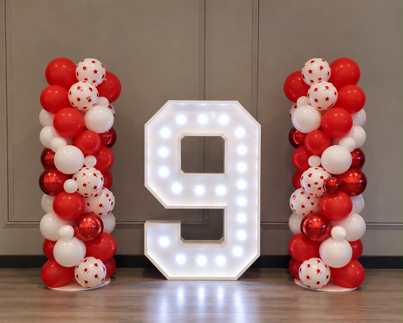 Birthday setup with red and white balloon towers and illuminated number display